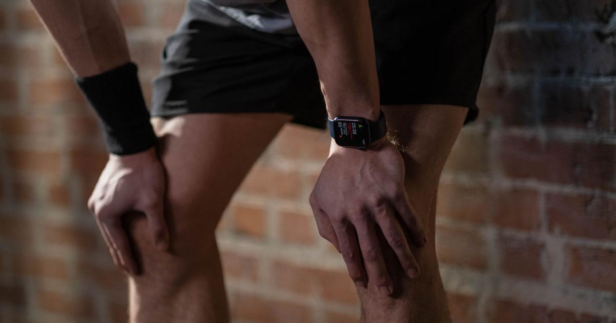 Close-up of a person checking a morning heart rate variability reading on a wrist-worn wearable device before getting out of bed.