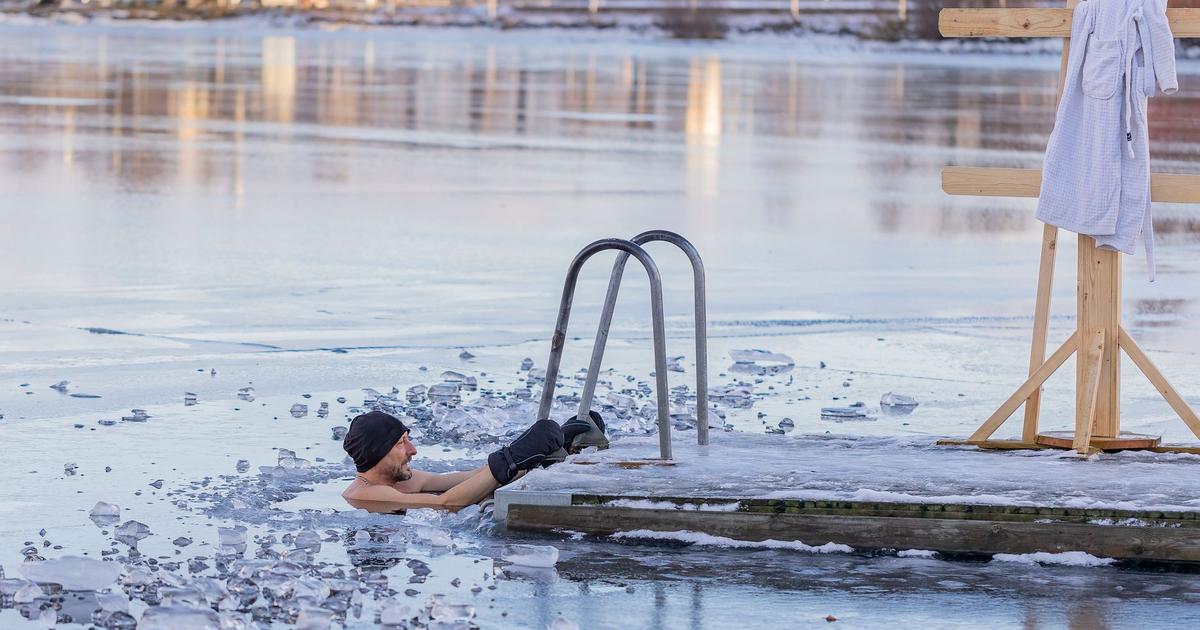 A person standing at the edge of an outdoor cold plunge tub filled with icy water, about to step in.