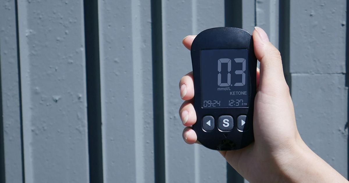 A person holding a small digital health monitor, the kind of consumer device that turns biohacking into measurable data.